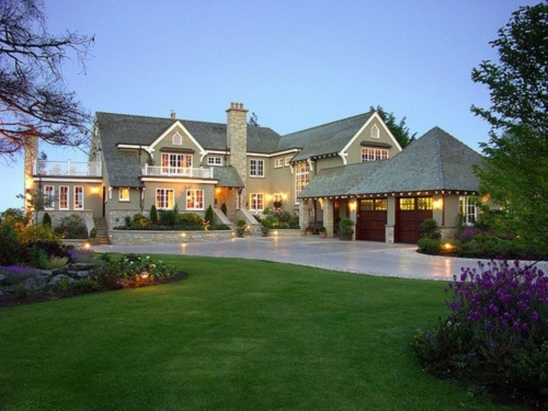 A large Georgia home at dusk with lit windows, a clean driveway and manicured lawn